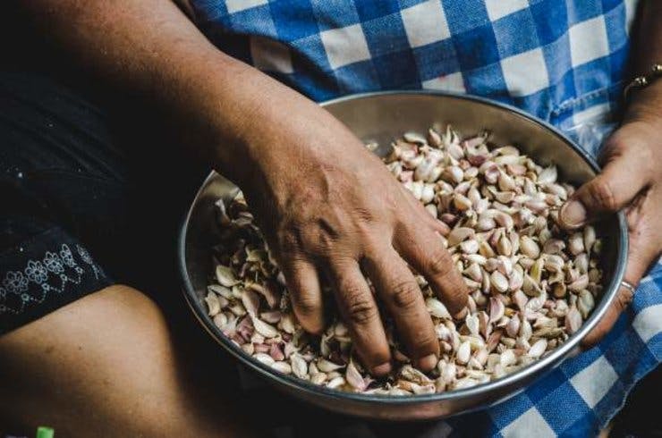 A hand stirs a bowl of nuts and seeds