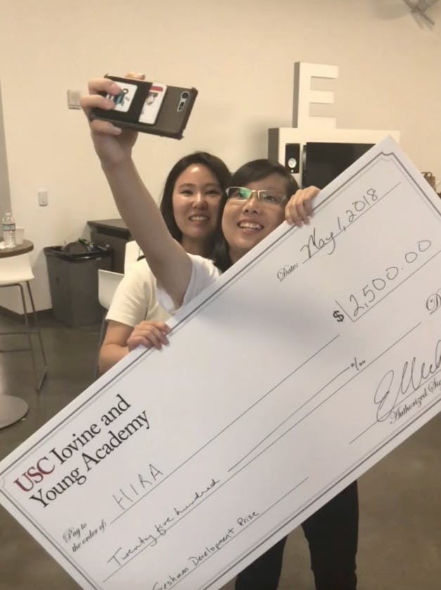 Two people hold up a jumbo-sized novelty check while taking a selfie
