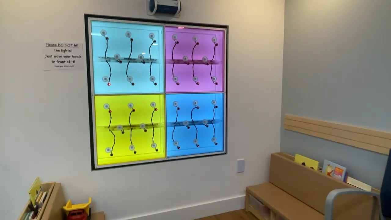 A grid of wires, lights, and buttons. The top left is light blue, the top right is purple, the bottom left is yellow, and the bottom right is a darker blue. 