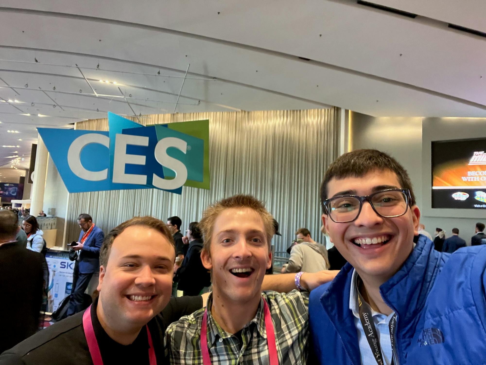 Three people at a tech conference posing in front of a logo 