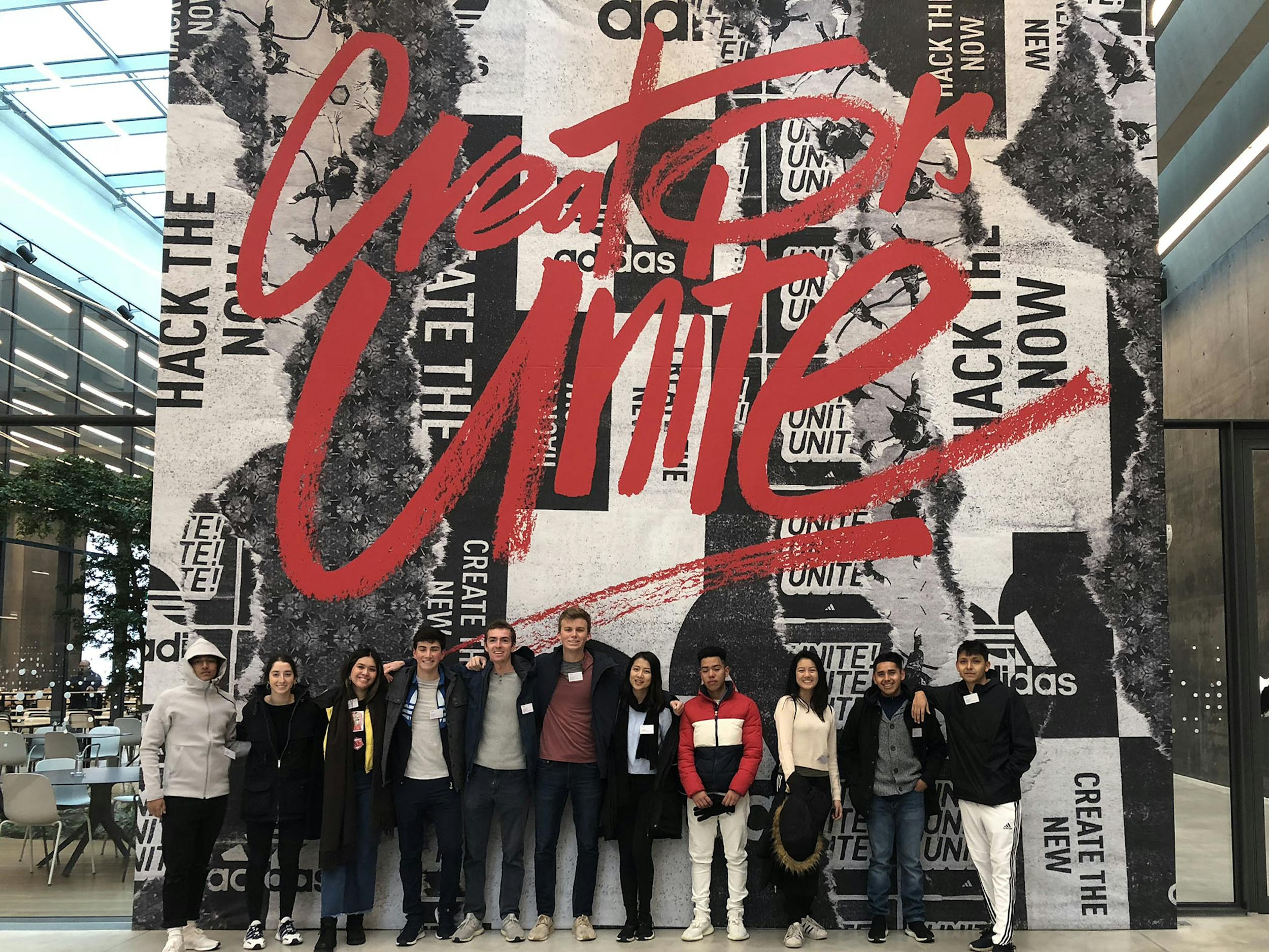 A group of students lined up in front of an art piece that says "Creators Unite"