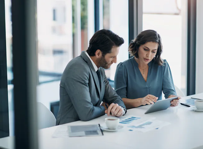 Image of two professionals seated at a table having a discussion.