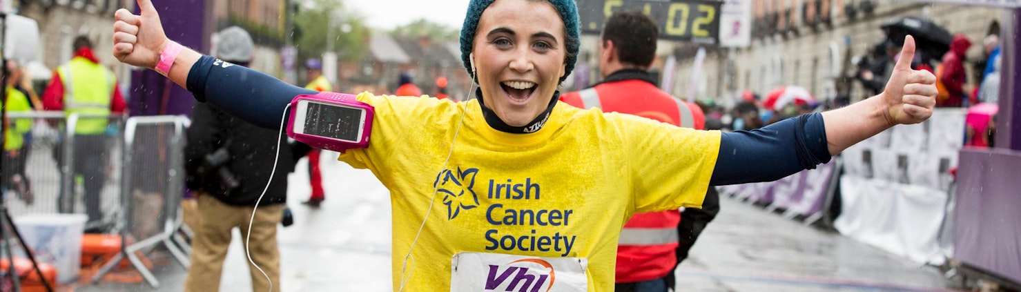 Lady finishing marathon in yellow Irish Cancer Society t-shirt
