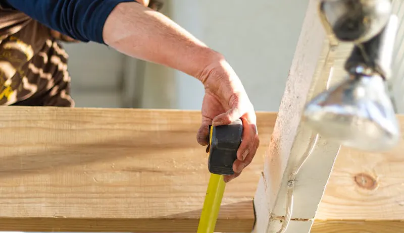 A close up image of a tradesperson measuring wood
