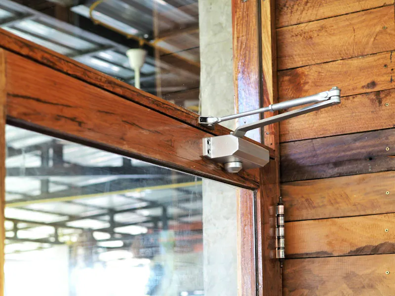 An image of a door closer on a wooden door