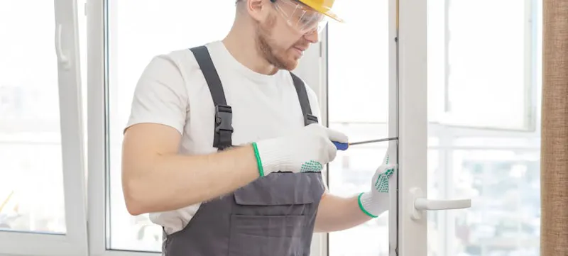 A man wearing a hard hat and using a screwdriver to replace a uPVC door handle