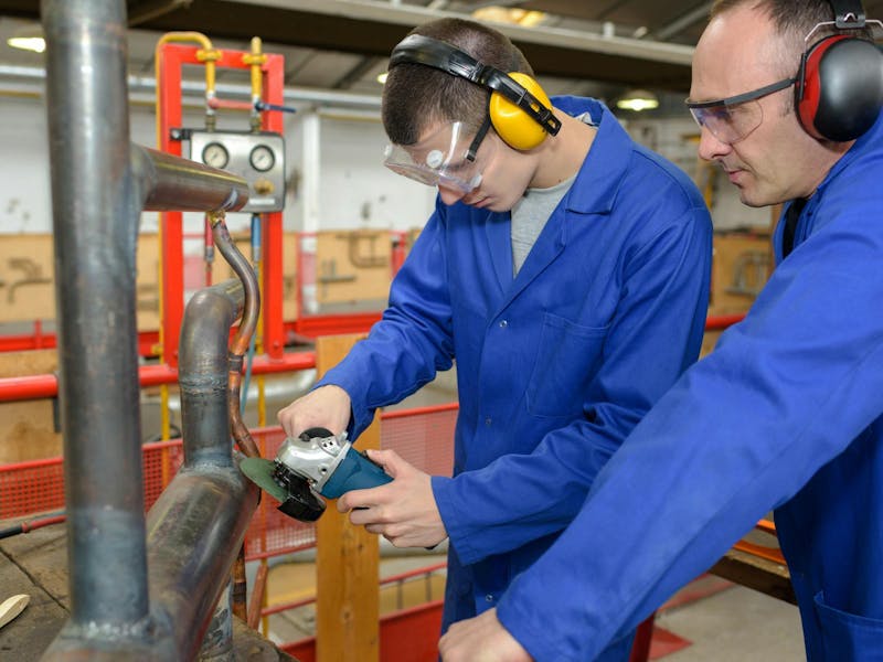 Two men using a mini circular saw whilst wearing ear protection