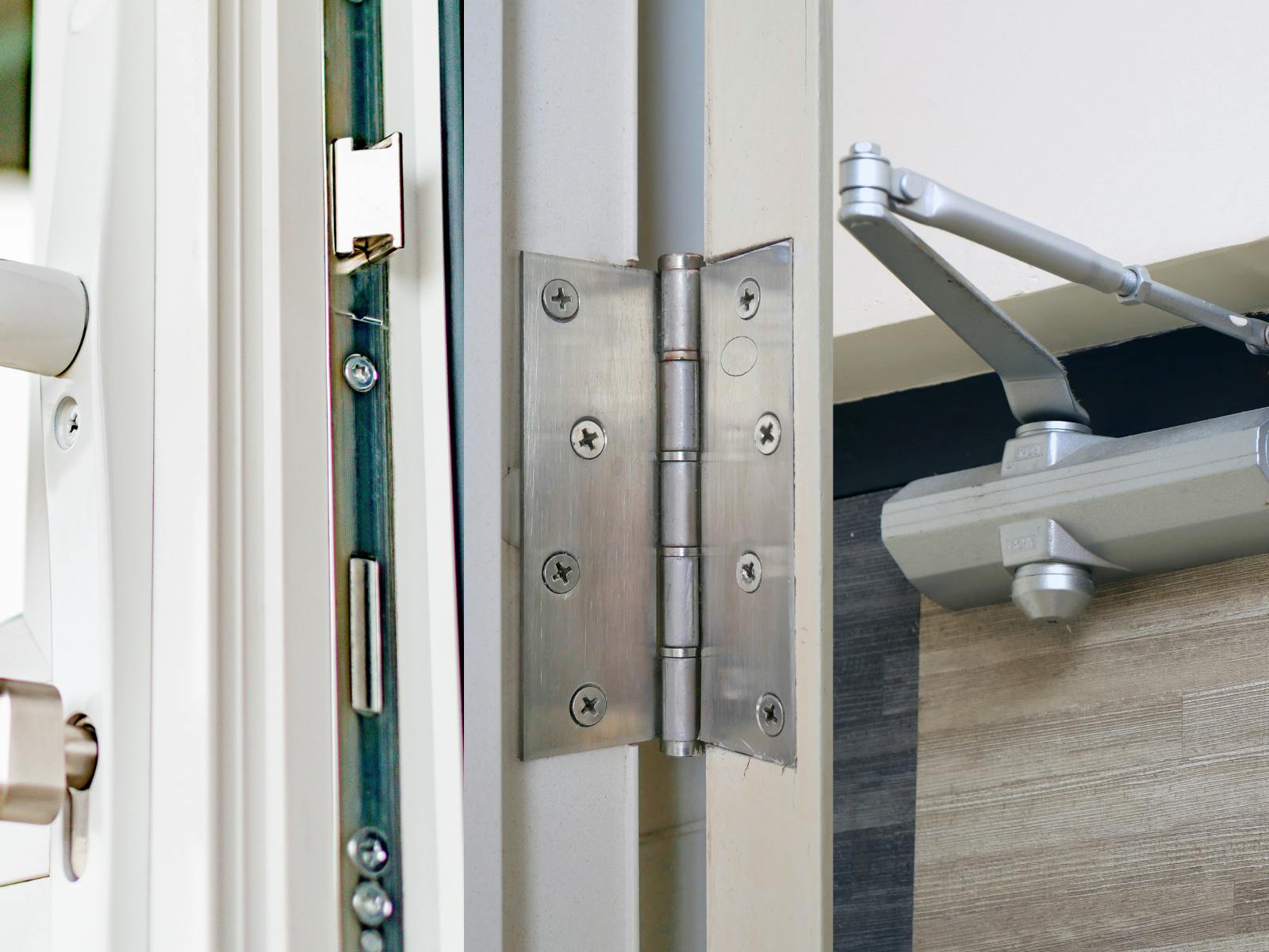 An image of a door lock, hinge, and closer