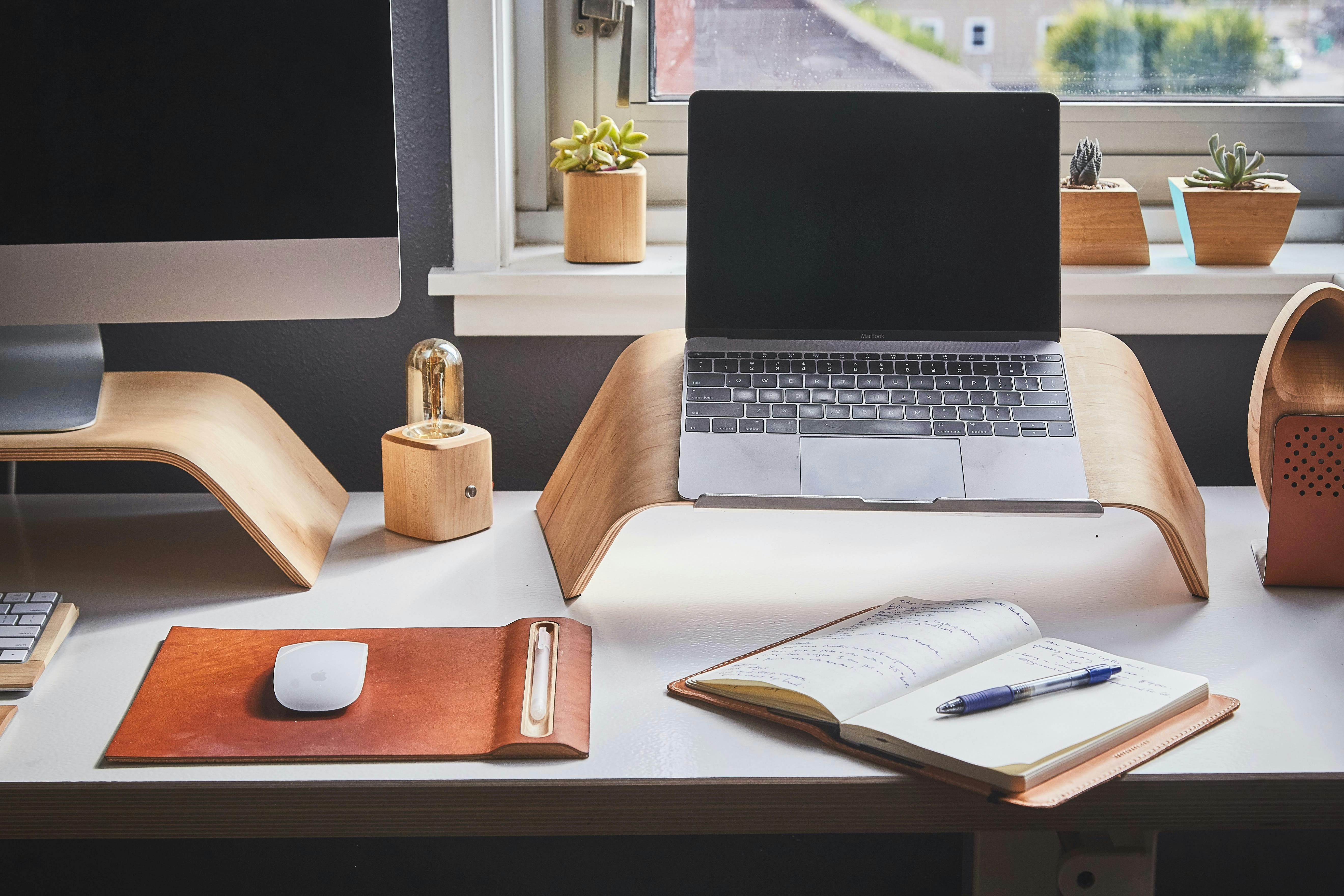 desk top with monitor, laptop, mouse, and open notebook on top of it