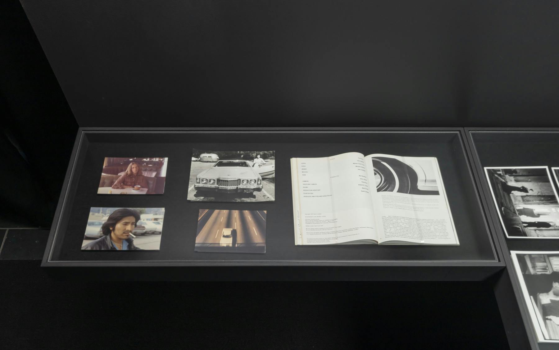 Installation view of a vitrine with archival photographs and documents.