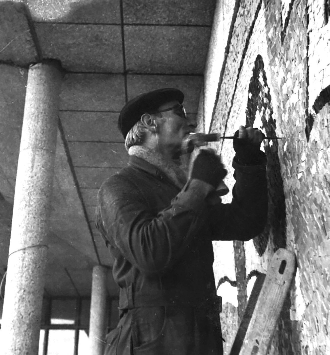 Black-and-white photograph of artist working on a mural