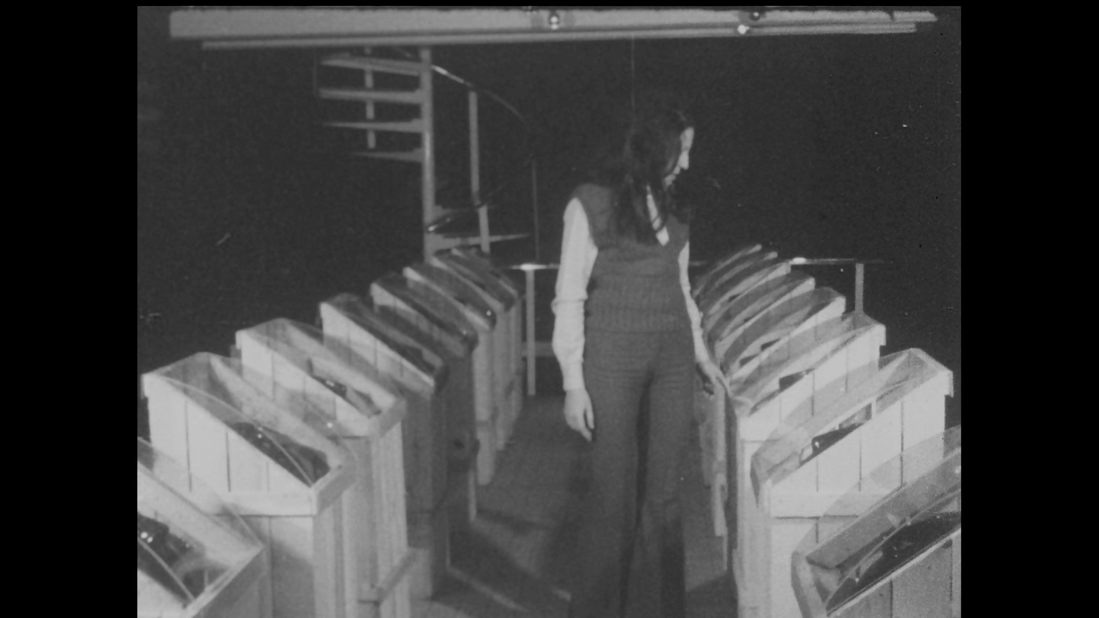 Black-and-white film still of young woman at gallery space