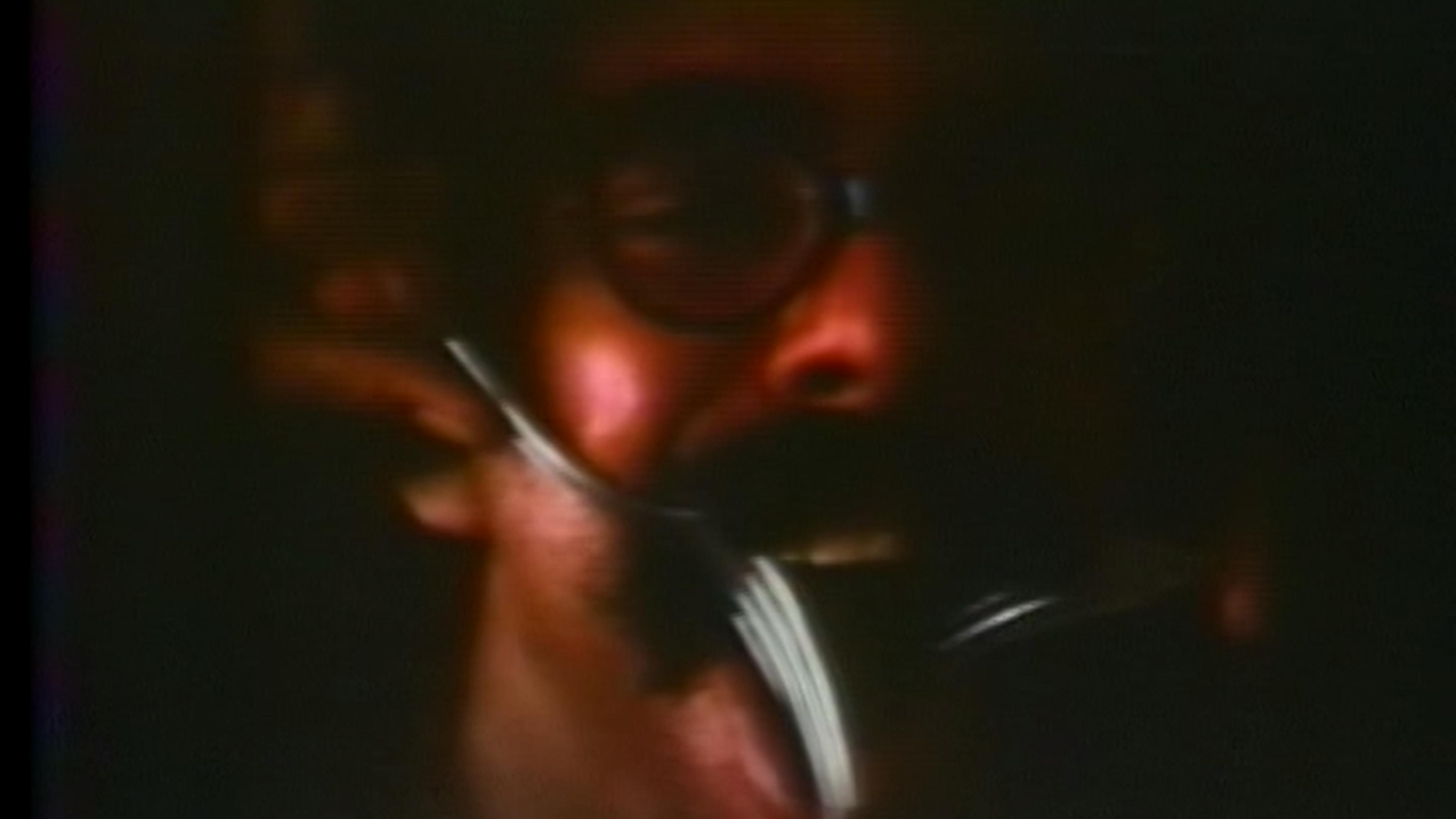 Color film still of man with a moustache holding a fork