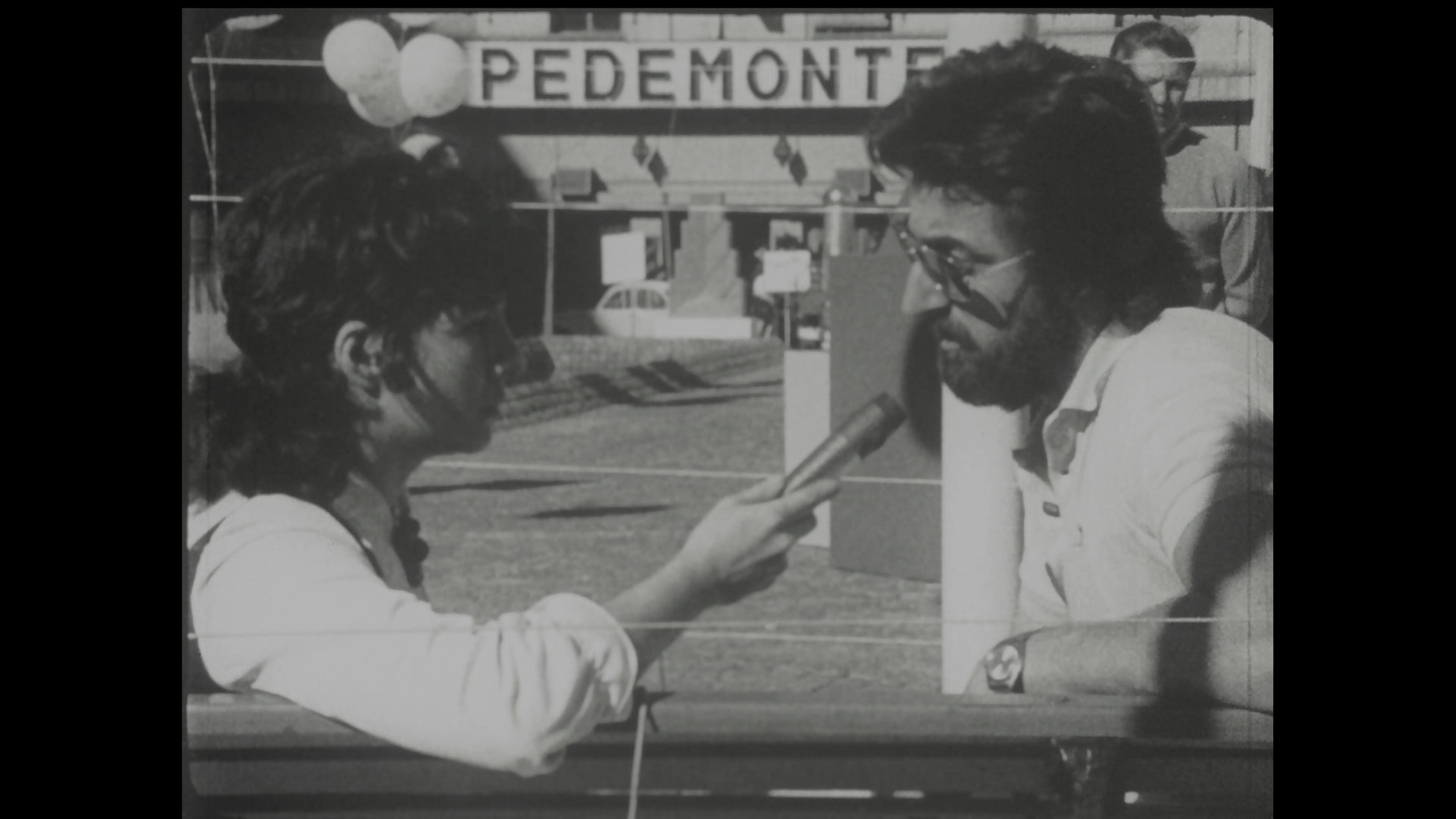 Black-and-white film still of woman interviewing man