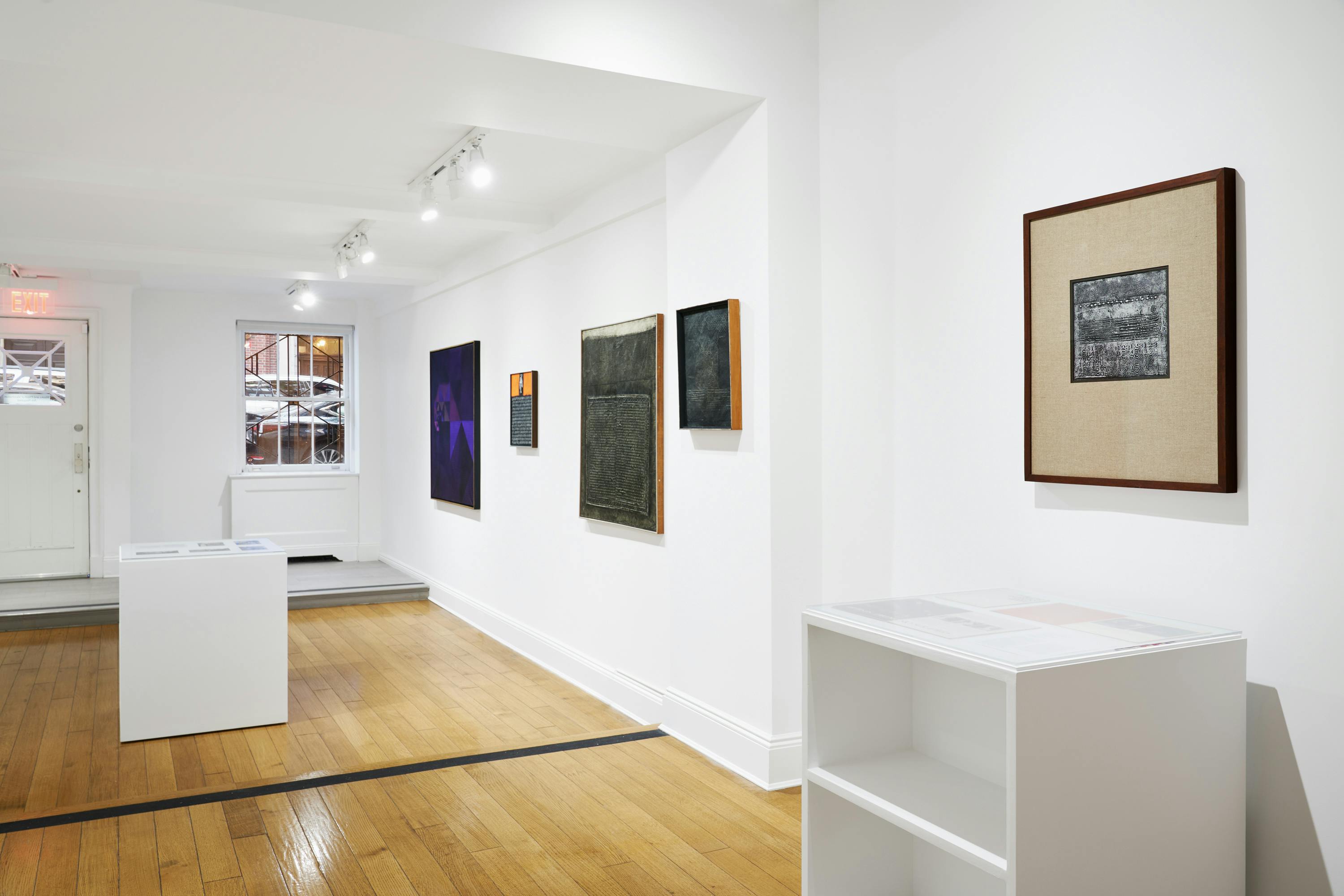 Installation view of José Antonio Fernández-Muro: Geometry in Transfer exhibition showing five paintings and two vitrines.