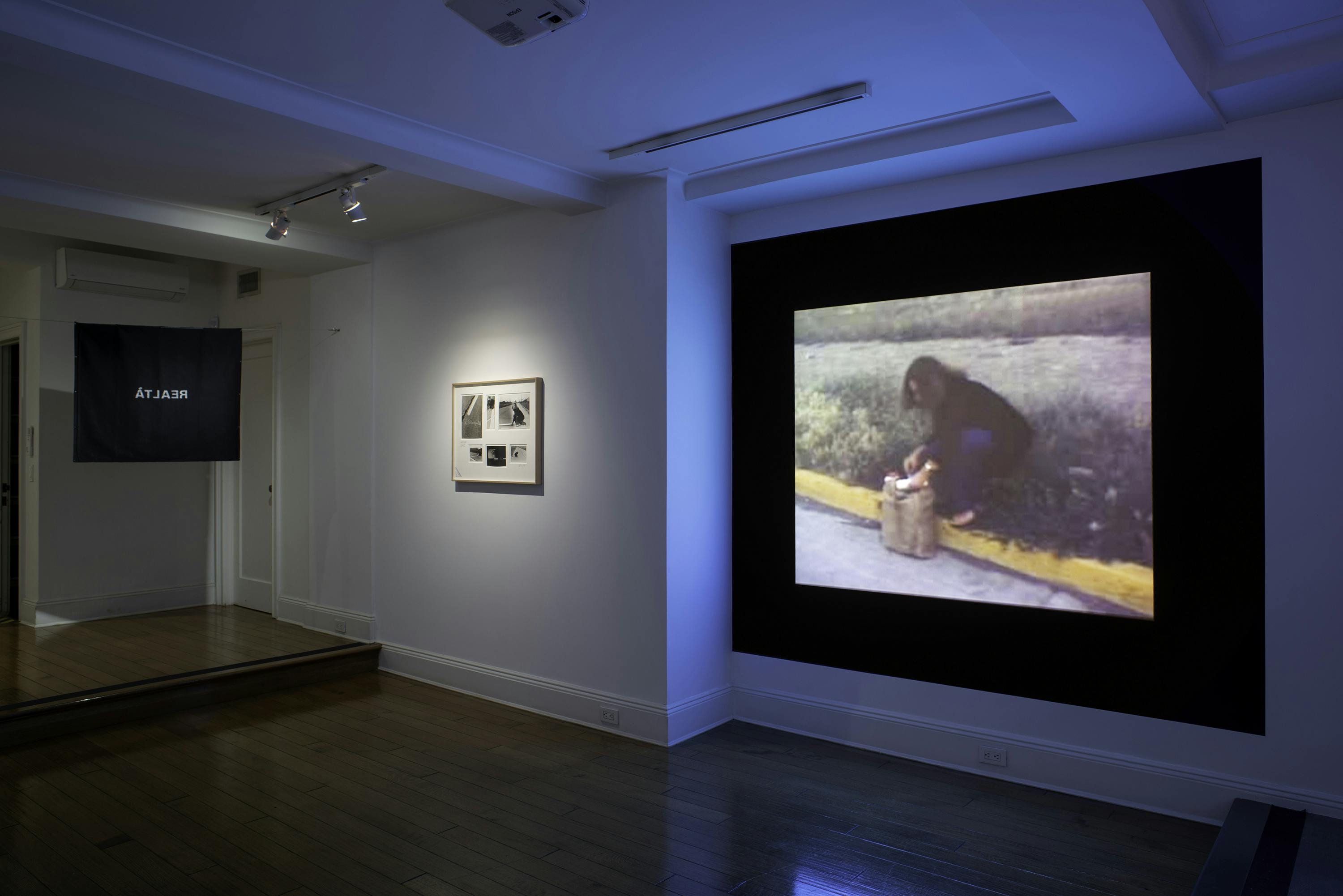 Left side view of a TV screen playing video, mounted and framed photographs, and a large video projection