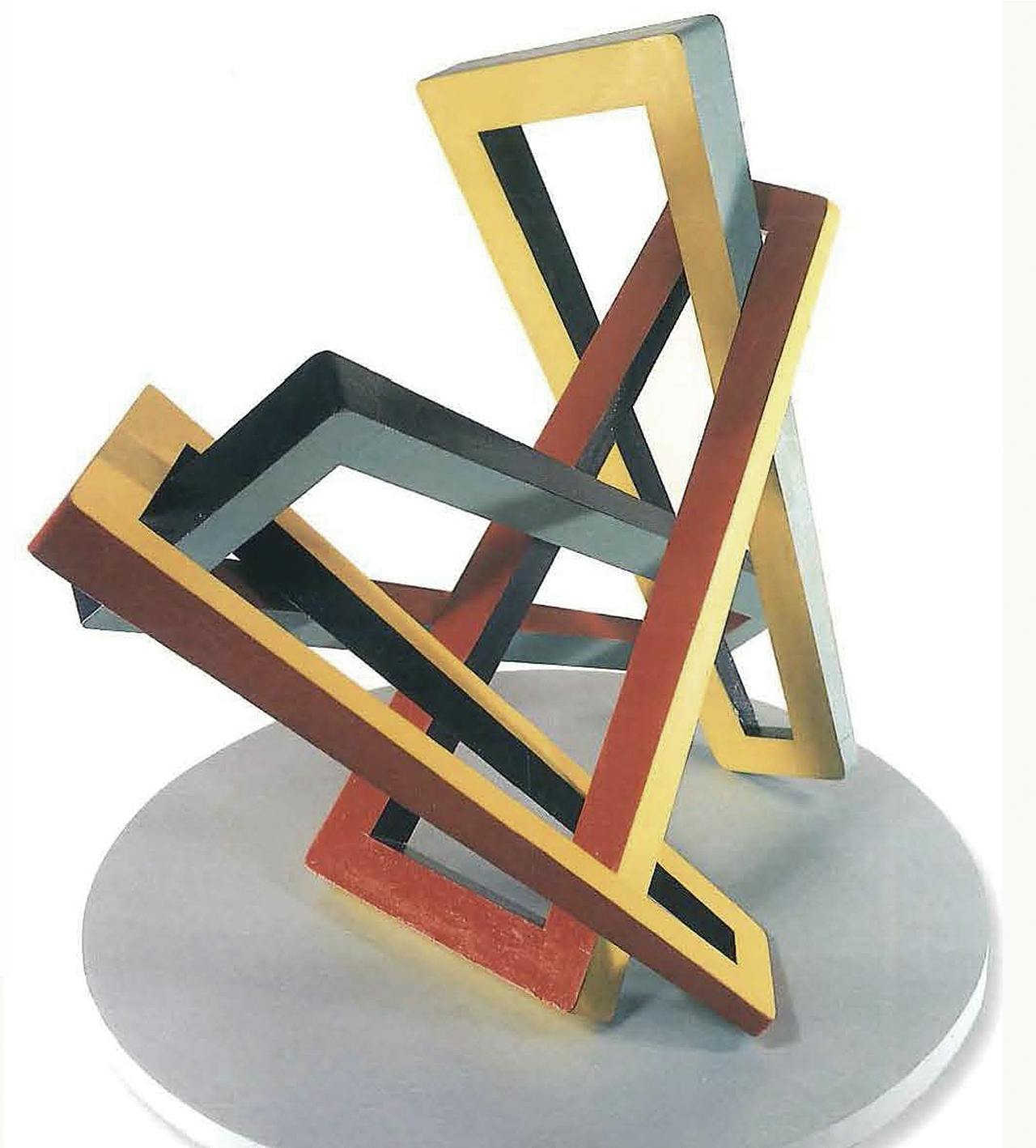A geometric sculpture made of interlocking, wood rectangles painted black, yellow, and red.