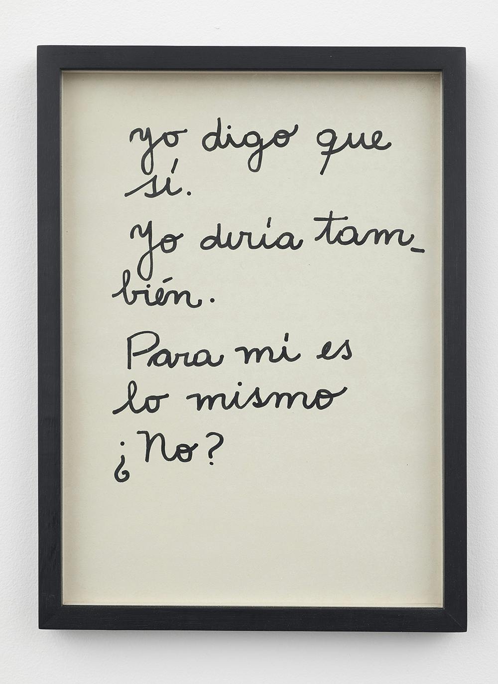 A white page with black cursive text is mounted mounted in a black frame and hung on a white wall. The text reads, “Yo digo que / sí. / Yo diría tam_ / bién. / Para mí es / lo mismo / ¿no?” (In English the text translates as, “I say yes. I say also. For me they are the same, are they not?”)