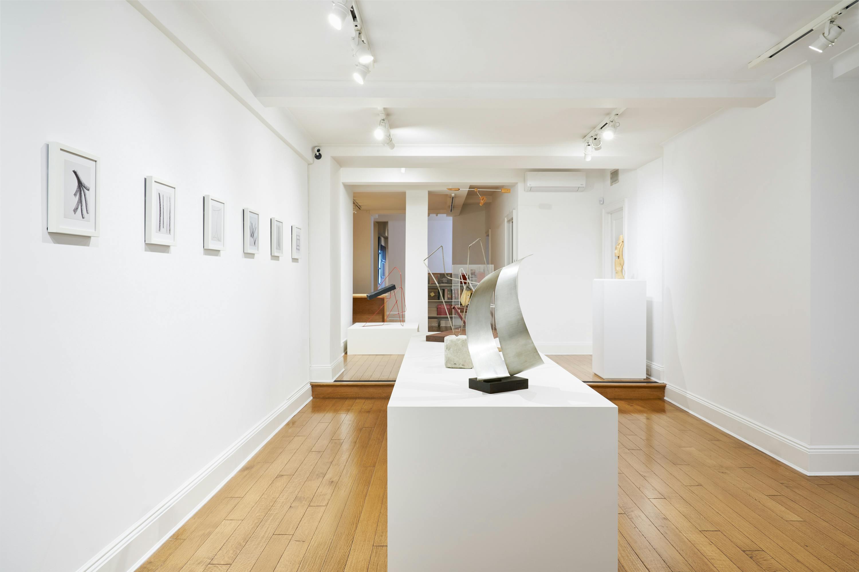 Gallery view of From Surface to Space exhibition showing one hanging sculpture, five free-standing sculptures, and six wall-mounted drawings.
