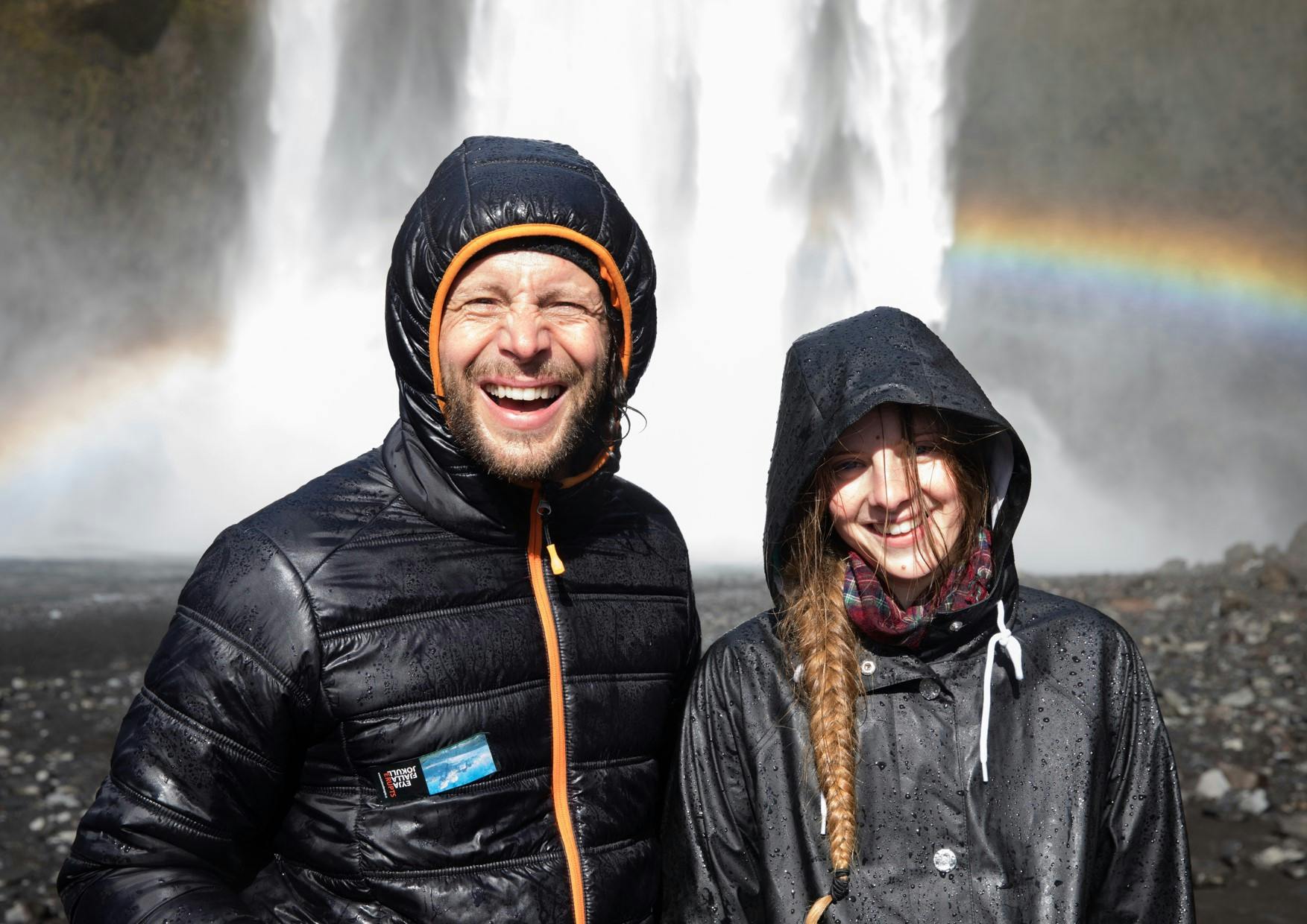 Icelandic waterfall with rainbow and people