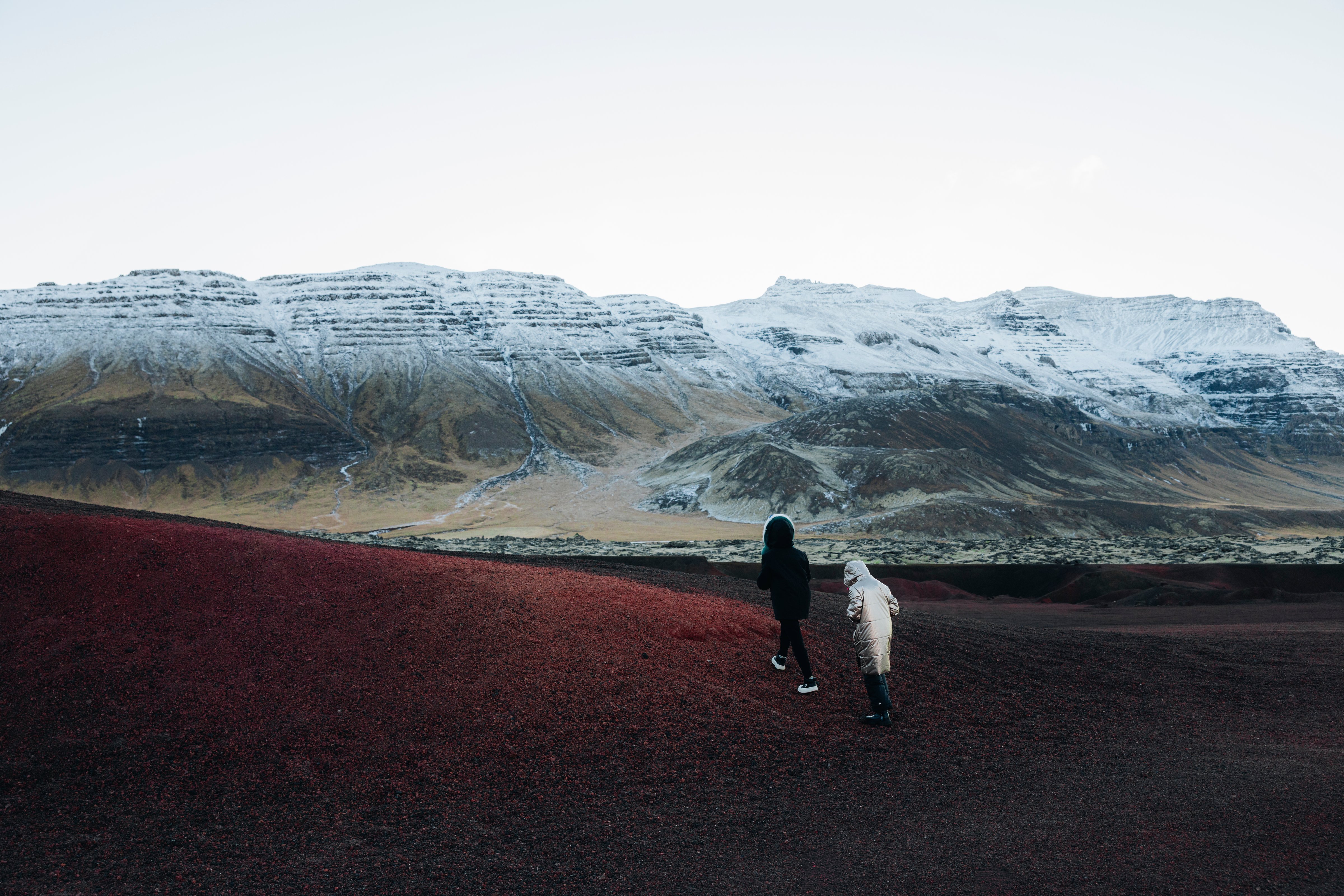 Par gengur á rauðum sandi hjá Arnarstapa