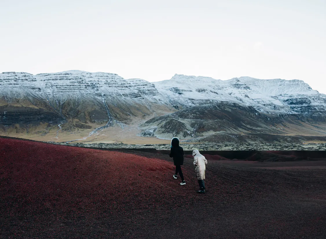 Par gengur á rauðum sandi hjá Arnarstapa