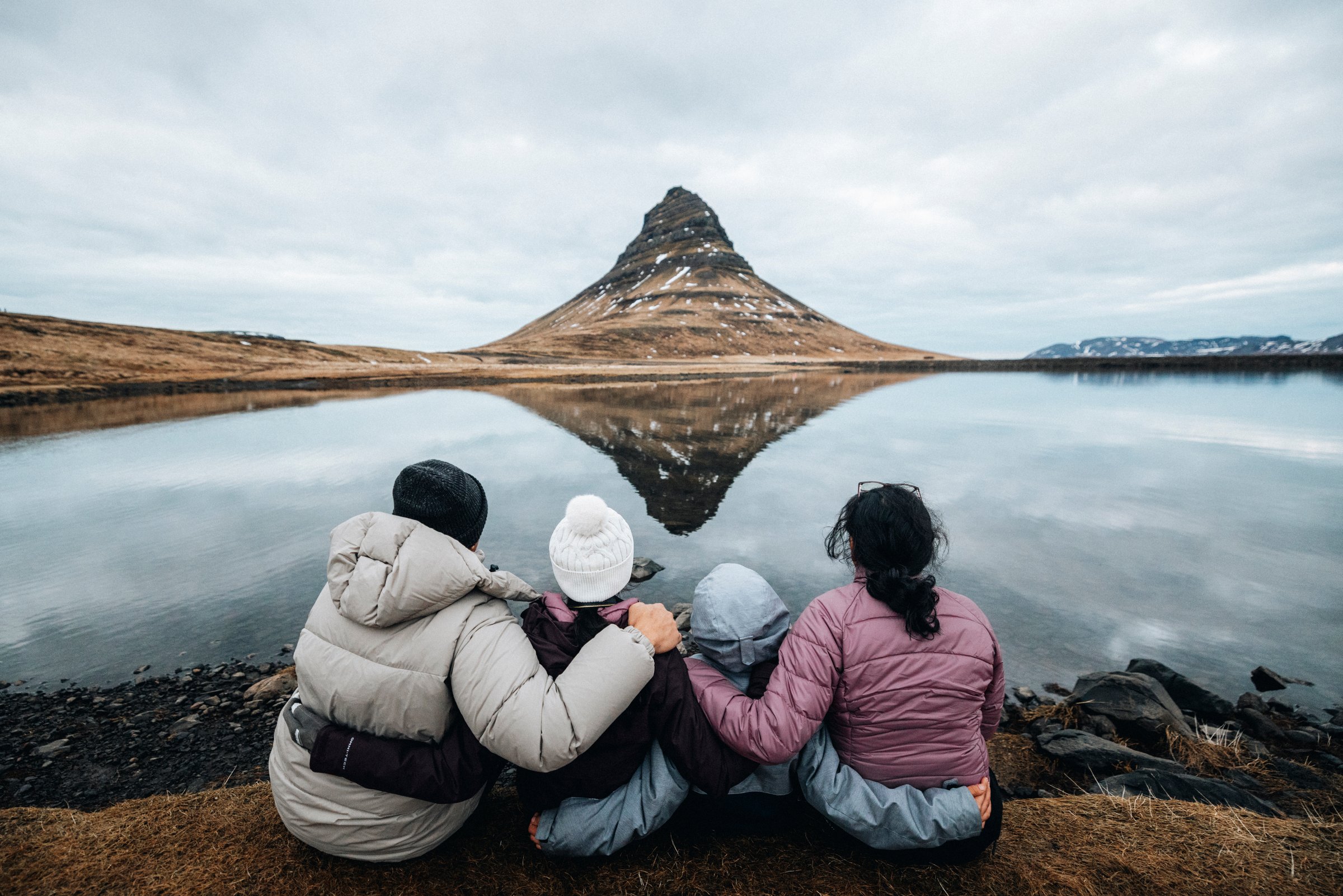 Þrír ferðamenn sitja og horfa á Kirkjufell