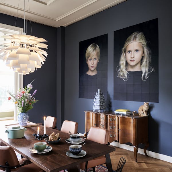 Eetkamer met donkere muur en twee foto's van kinderen als wanddecoratie