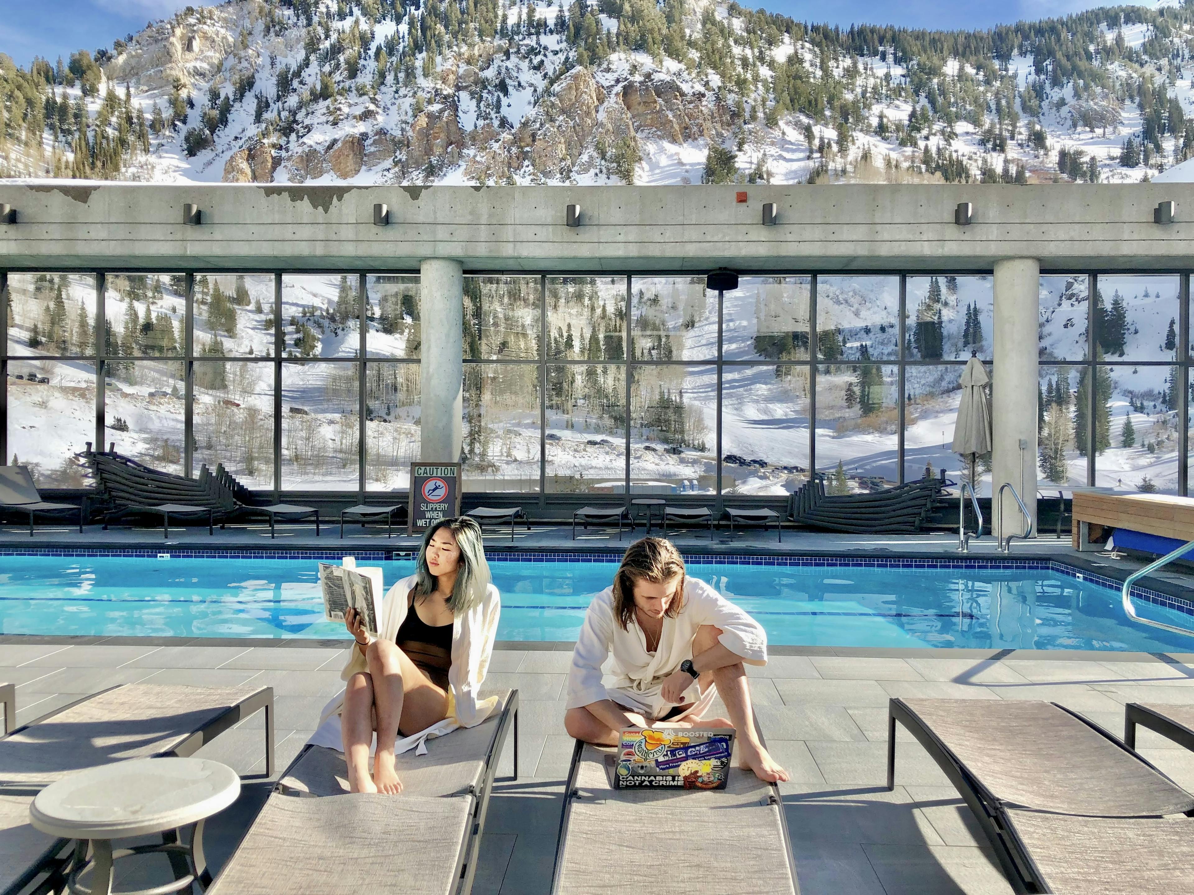 My partner and I sitting at a pool with snowy mountains in the background. 