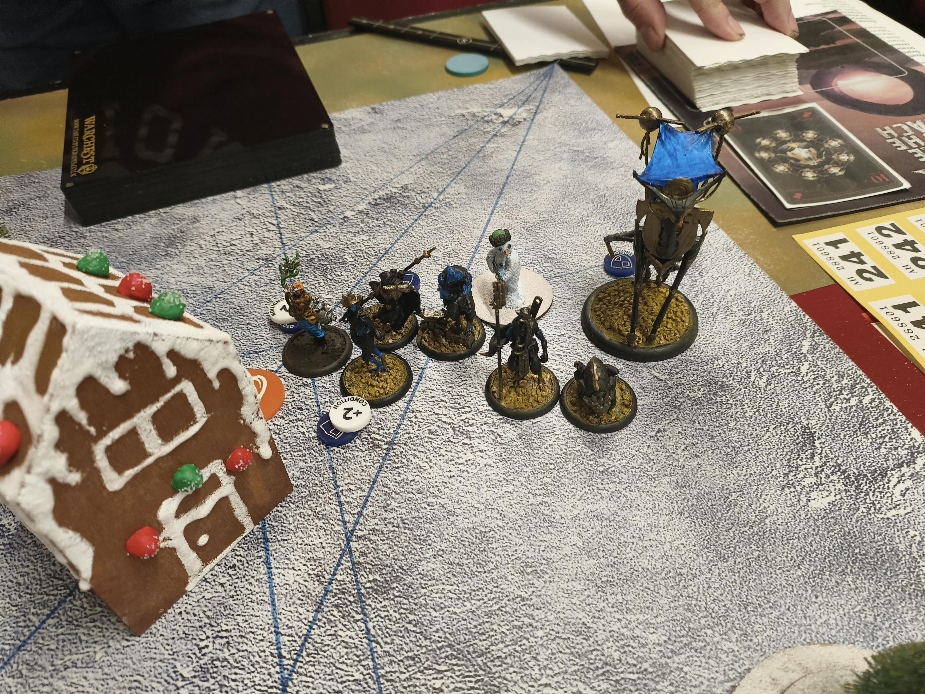 A Malifaux board with a Gingerbread house and a Tiri crew