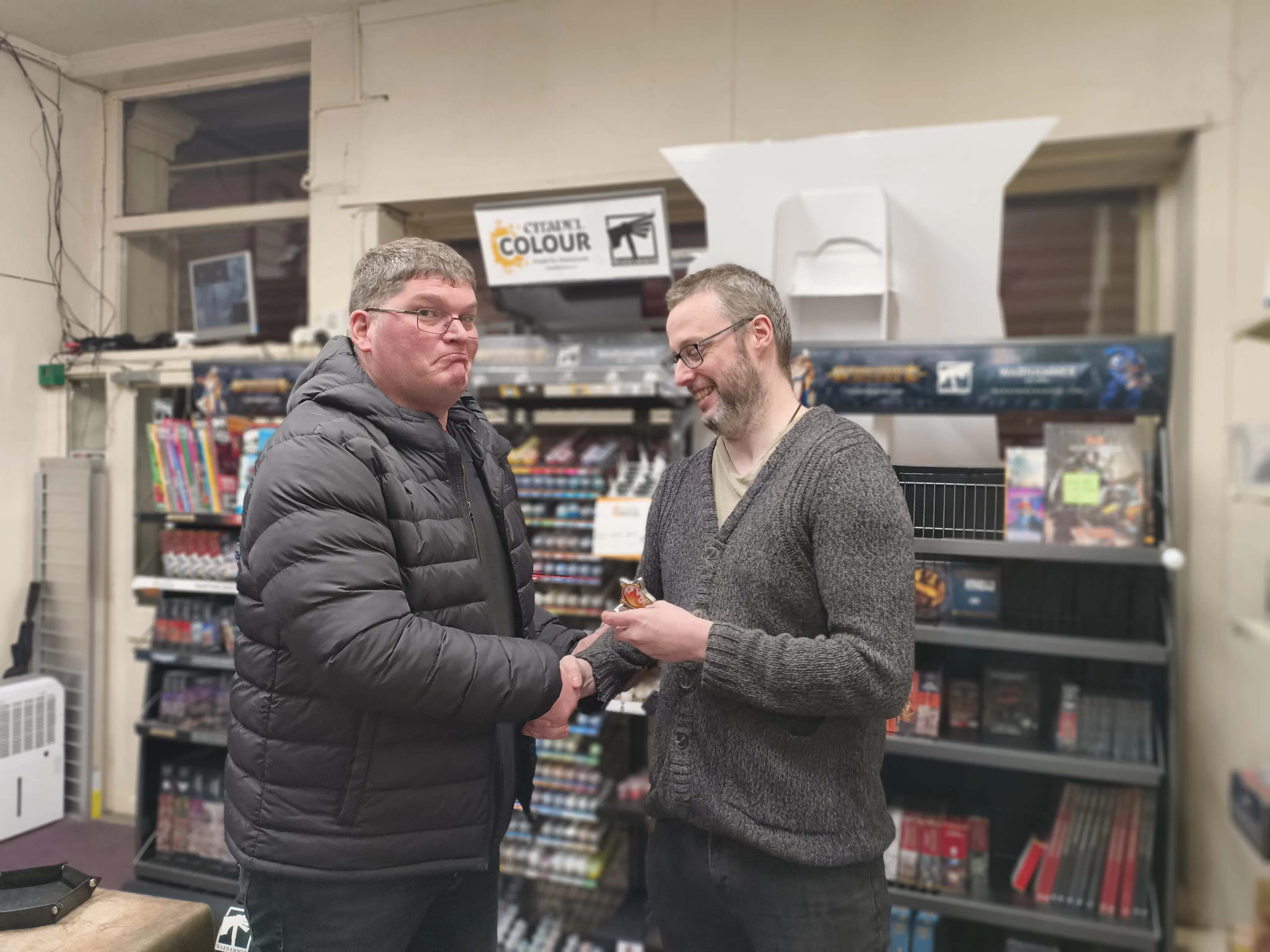 One wargamer comically crushing another's hand while shaking it