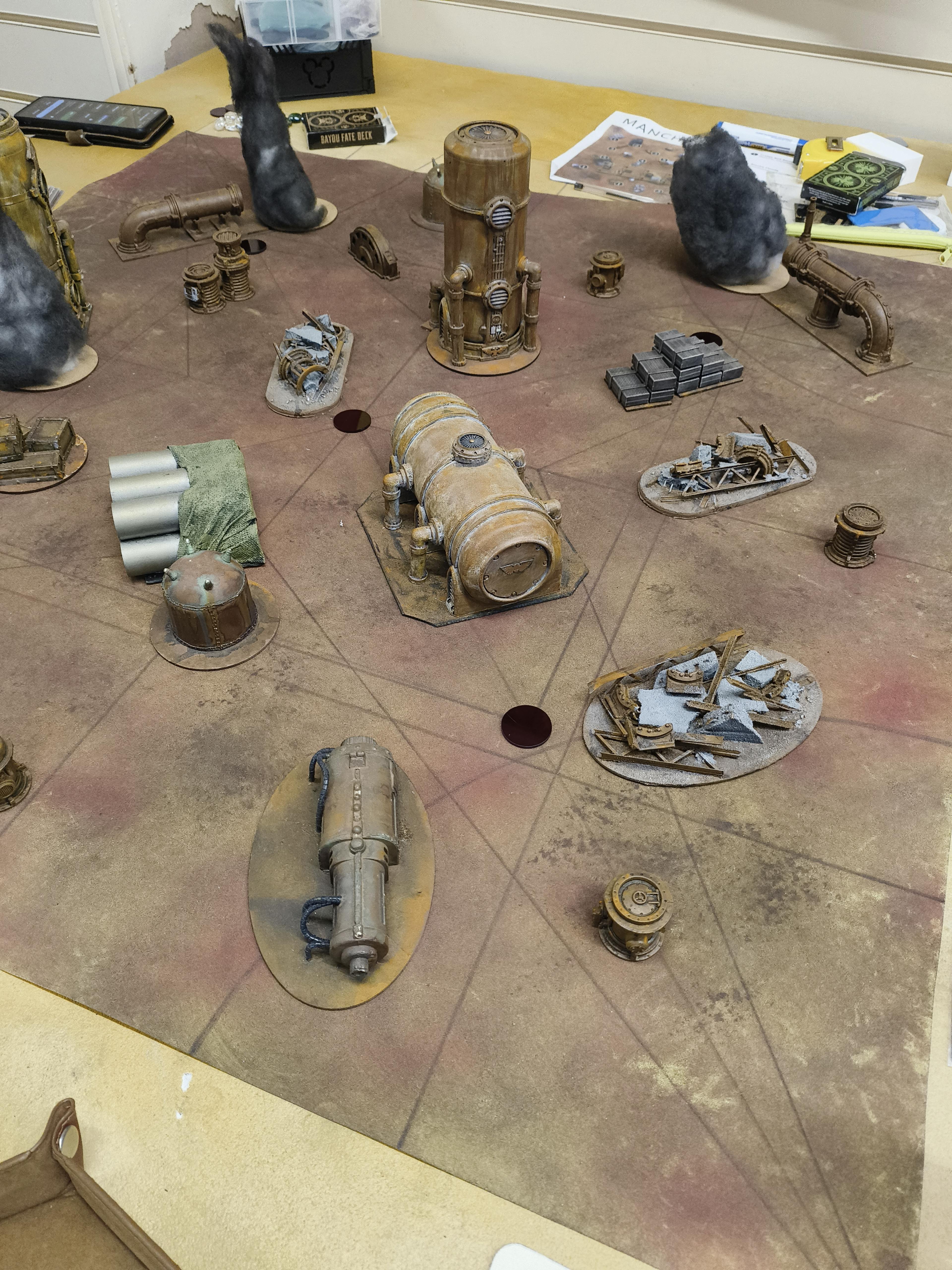 A Malifaux game board set up with industrial terrain.