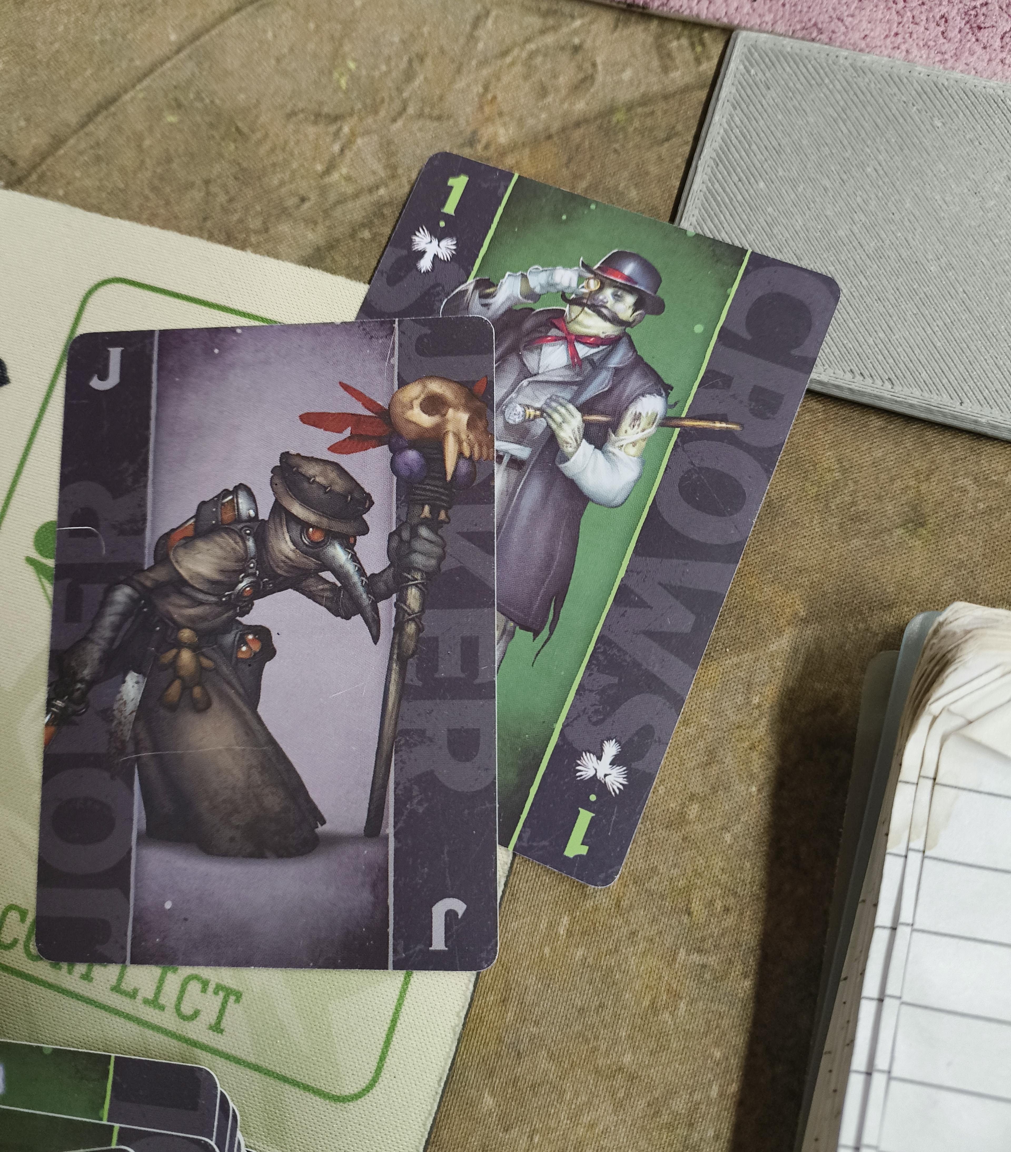 A Black Joker and a 1 card from a Malifaux fate deck.
