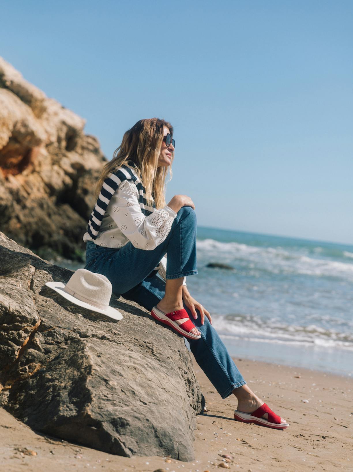 Model sitzt am Strand auf einem Fels