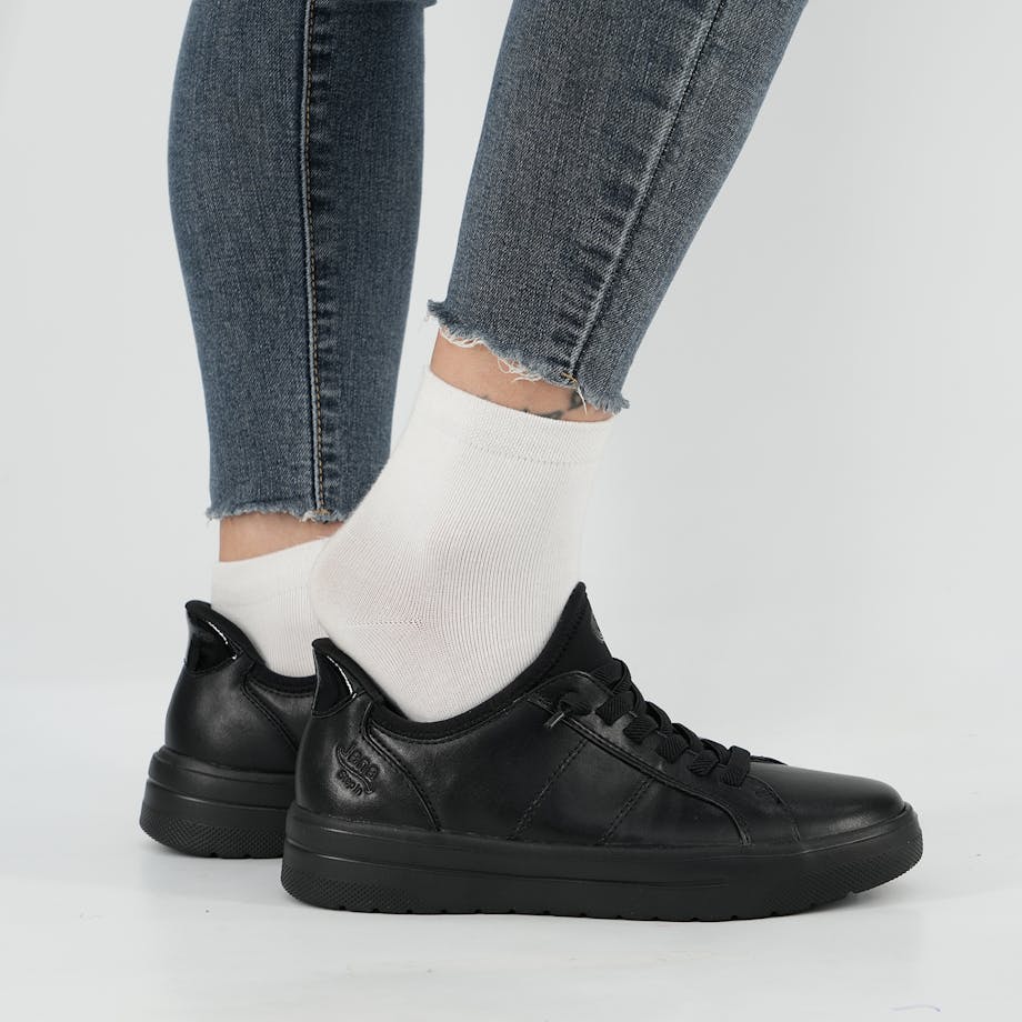 Person steigt freihändig in schwarzen Jana Schuh – bequemes Anziehen ohne Bücken dank Step in Technologie.