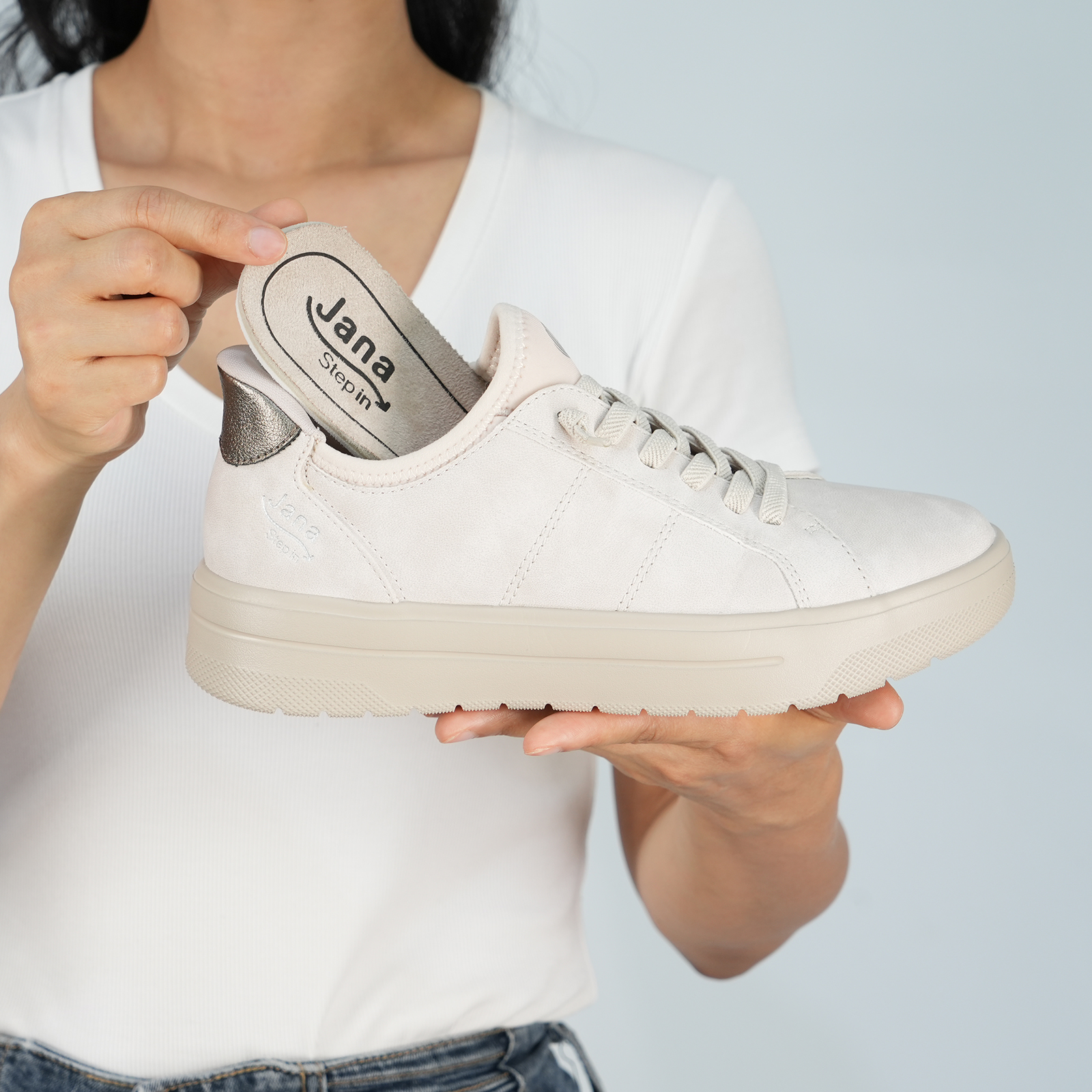 Person zeigt, dass man bei dem beigen Jana Step in Sneaker eine herausnehmbare Sohle hat – so kann man auch seine eigenen Einlagen verwenden.