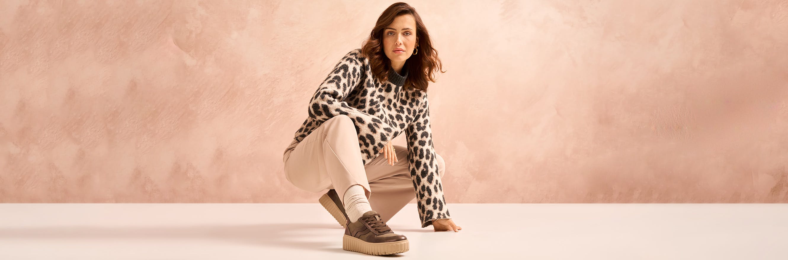 Model hockt und trägt einen braunen Sneaker