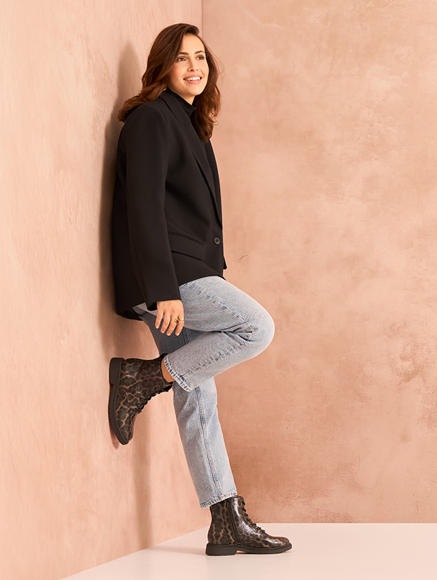 Model lehnt an einer Wand mit Schnürstiefeletten mit Leopardenmuster