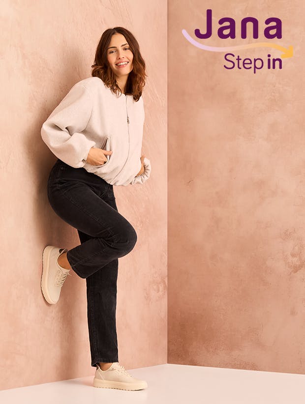 Model lehnt an einer Wand und trägt beige Jana Step in Sneaker