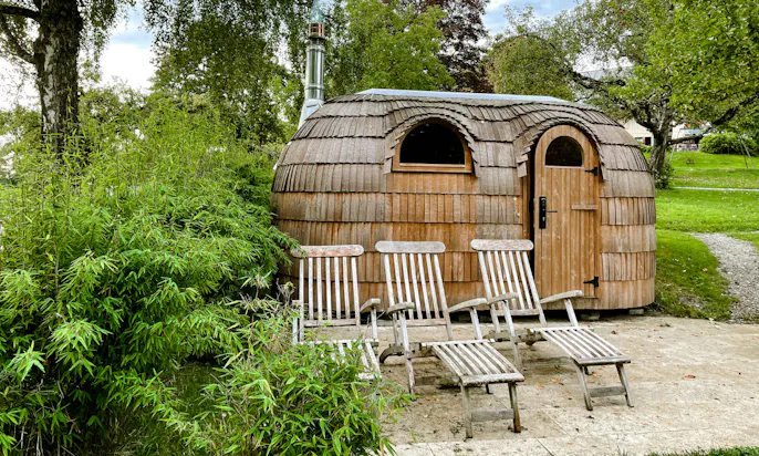 Tiny House mit Liegestühlen im Vordergrund