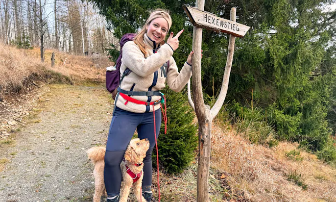 Frau und Goldendoodle wandern auf dem Harzer Hexen Stieg auf der 4. Etappe im Winter
