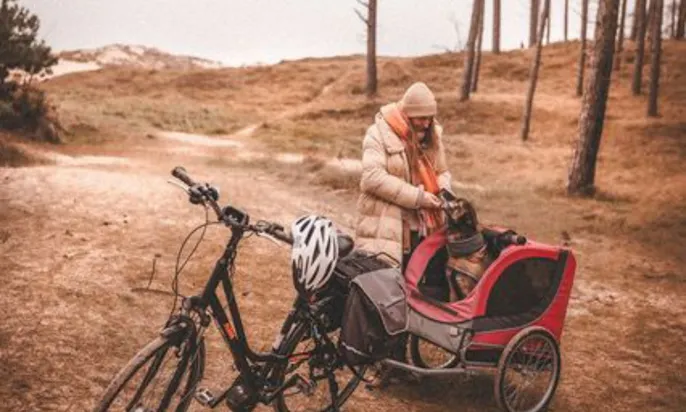 Einer Frau mit ihrem Fahrrad und einem Anhänger mit Hund