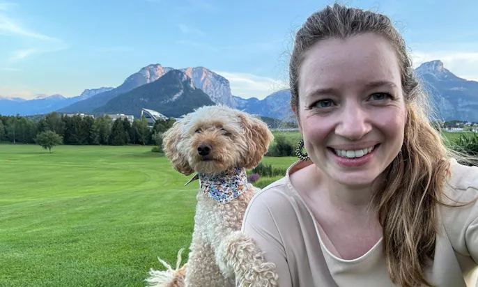 Selfie von Frau mit Hund und im Hintergrund sind Berge