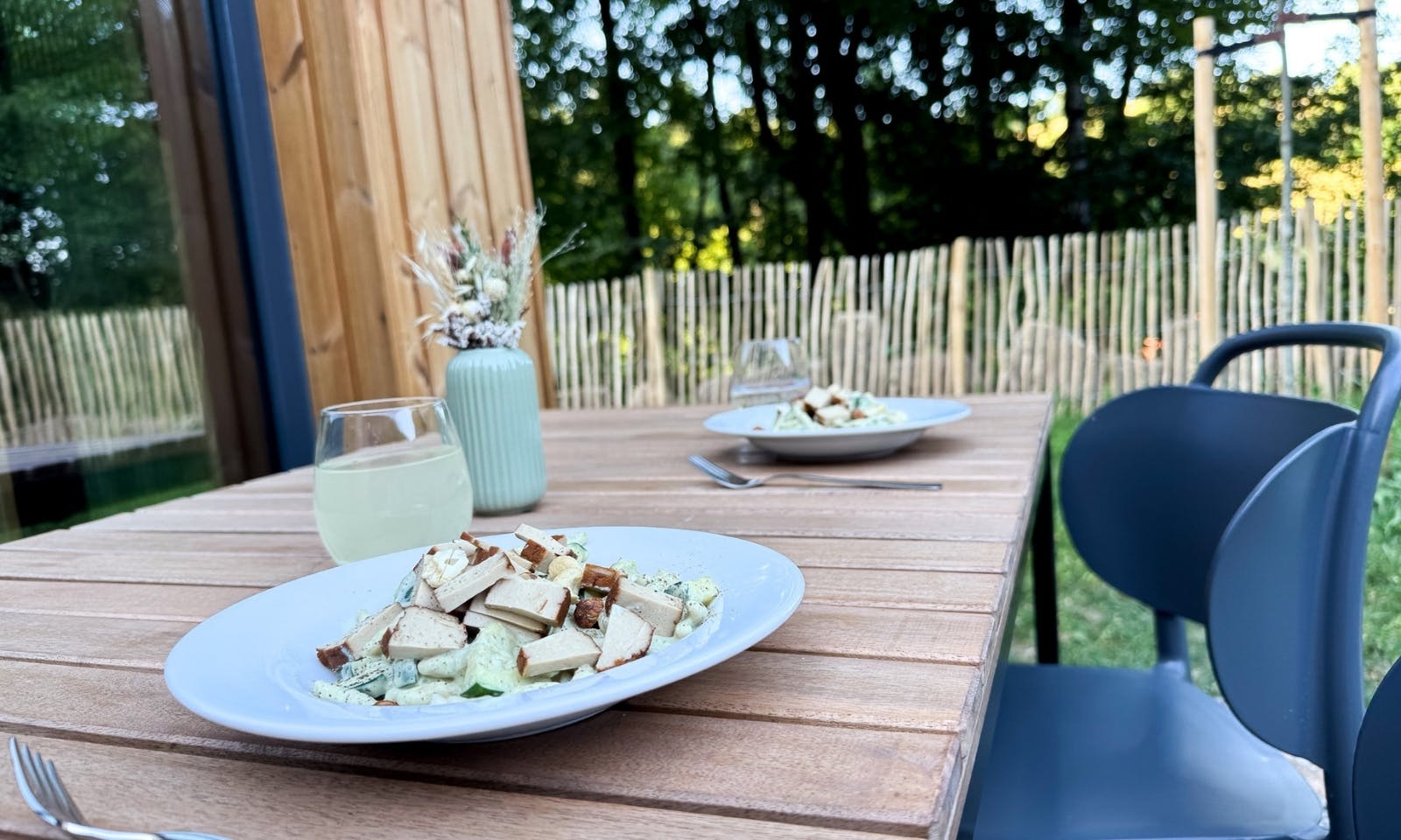 Ein Tofu-Gericht auf einem Esstisch im Garten des DOGGIA Tiny Houses