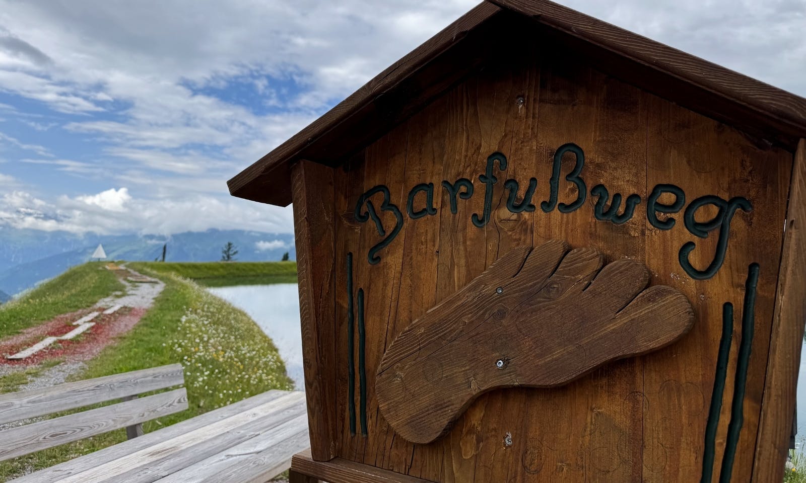 Ein Schild, das den Beginn eines Barfußwegs am Spiegelsee markiert