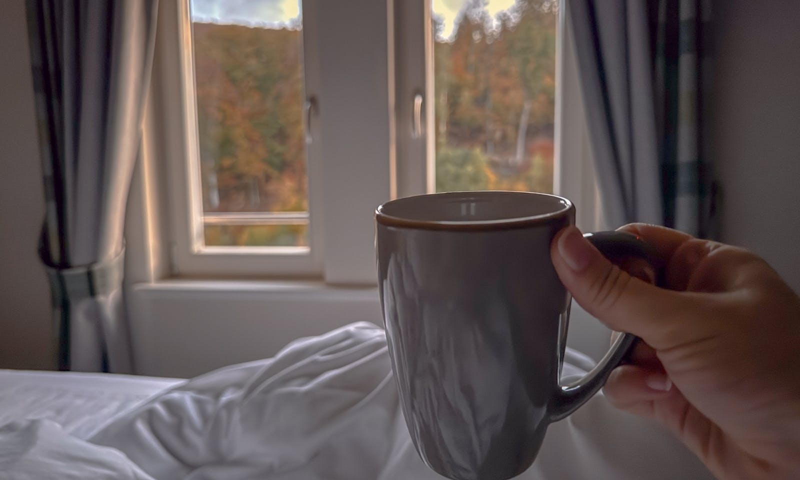 Tasse mit Kaffee im Bett in einem der Zimmer im Hotel & Spa Suiten FreiWerk in Stolberg