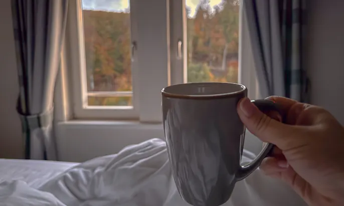 Tasse mit Kaffee im Bett in einem der Zimmer im Hotel & Spa Suiten FreiWerk in Stolberg