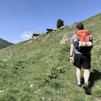 Mann beim Wandern mit Rucksack und Hundedecke