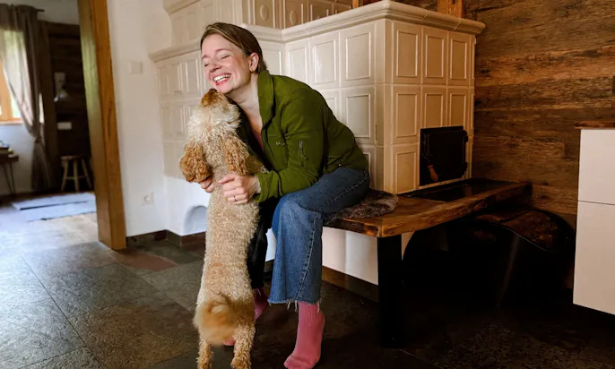 Frau und Goldendoodle vor dem Kamin im Eichen Chalet