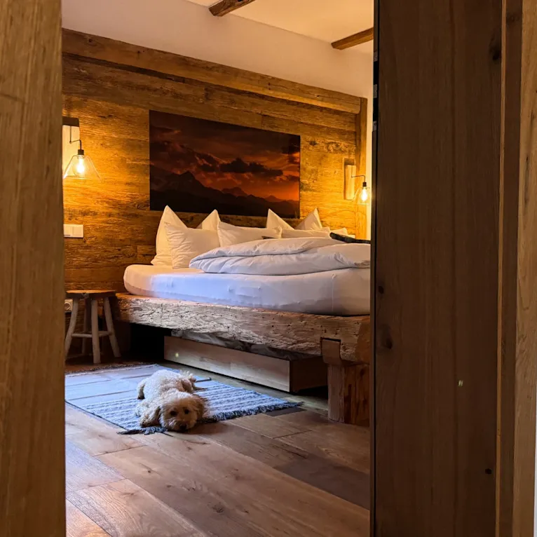 Goldendoodle liegt vor dem Bett im Eichenchalet